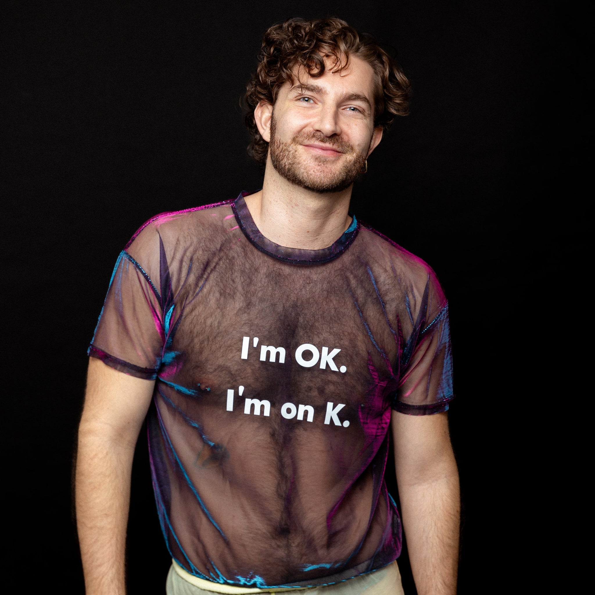 Person wearing a sheer shirt with text 'I'm OK. I'm on K.' against a black background